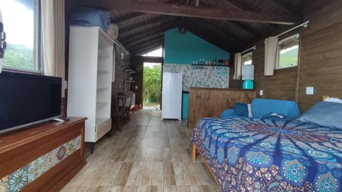 um quarto com uma cama e uma televisão de ecrã plano em Koa Cabana praia do luz em Imbituba