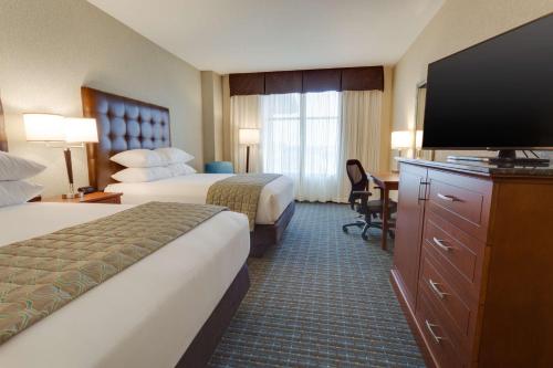 a hotel room with two beds and a flat screen tv at Drury Plaza Hotel St. Louis St. Charles in St. Charles