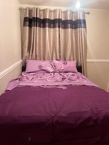 uma cama roxa num quarto com uma janela em A&G em Thurcaston