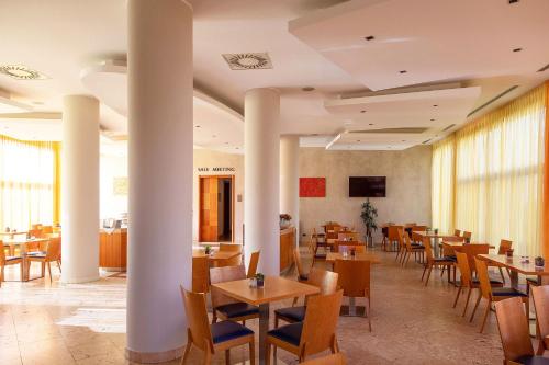 a restaurant with tables and chairs and a tv at Best Western Hotel Fiera Verona in Verona