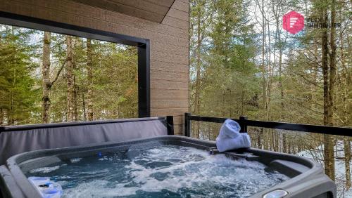 a jacuzzi tub on a deck with a window at Le Bleu Bourgeois de Portneuf - Natural Elegance - Hot tub, sauna and pool in Pont-Rouge