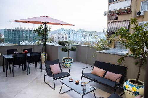 balkon z krzesłami, stołami i parasolem w obiekcie Terra'Vista Apartments w Tiranie
