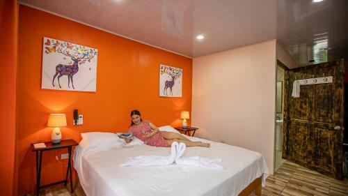 a woman sitting on a bed with a cat at Cabañas Río Escondido en La Fortuna in Fortuna