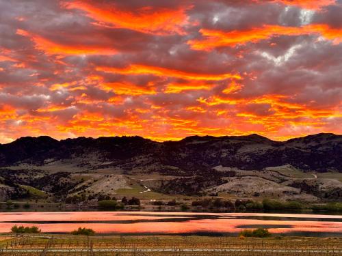 a sunset over a field with mountains in the background at Glamping Dome - Rosé in Cromwell