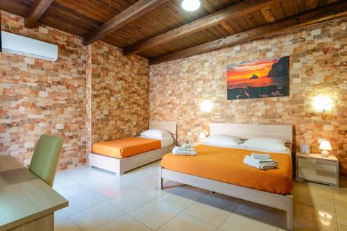 a bedroom with two beds and a brick wall at Domos La Corte Ghibellina in Iglesias