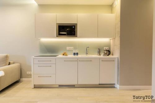 a white kitchen with a sink and a microwave at Royal Hill Residence in Zakopane