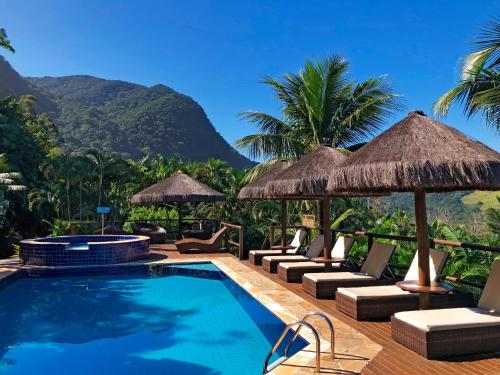 a resort swimming pool with chairs and umbrellas at Ilha de Toque Toque Eco Hotel in São Sebastião