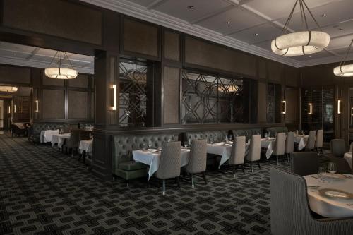 a dining room with white tables and chairs at Waldorf Astoria Orlando - An Official Walt Disney World Hotel in Orlando