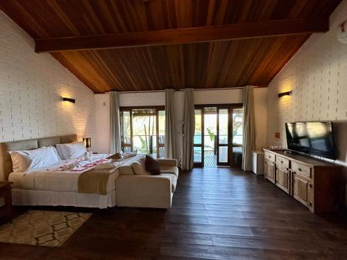 a bedroom with a bed and a couch and a television at Ilha de Toque Toque Eco Boutique Hotel & Spa in Toque Toque Grande