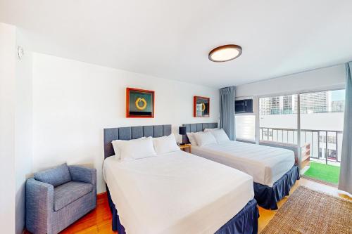 a hotel room with two beds and a chair at Waikiki Haven in Honolulu