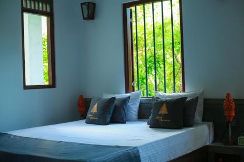 a bedroom with a bed with pillows and a window at Charming dark lodge in river in Weligama