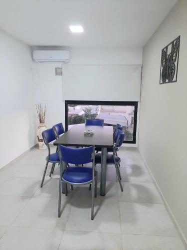 a dining room with a table and blue chairs at Departamento FICO 2 in Sunchales