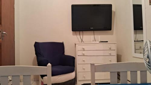 uma sala de estar com uma cadeira azul e uma televisão em Casa Caraguatatuba Nelson em Caraguatatuba