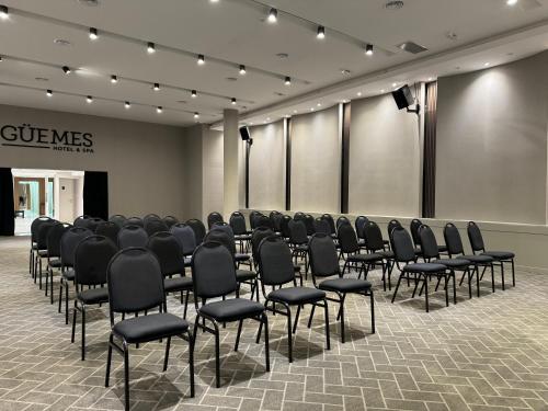 a conference room with black chairs and a stage at Guemes Hotel & Spa in Salta