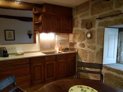 a kitchen with wooden cabinets and a table and a sink at Solar dos Pedrosos in Vila Chã