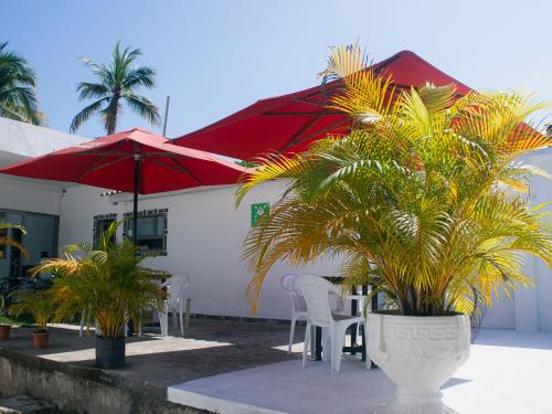 a patio with chairs and red umbrellas and palm trees at ZABDI COVEÑAS in Coveñas
