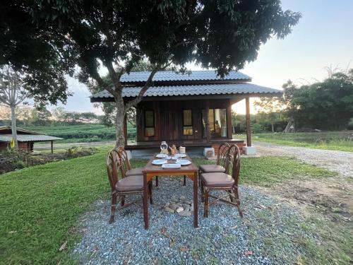 a table and chairs in front of a house at Punpawn ปั๋นปอนด์ Farm Stay in Chiang Saen