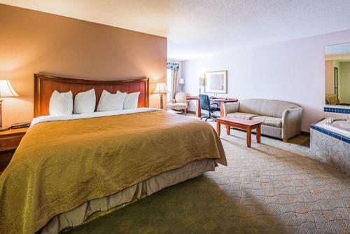 um quarto de hotel com uma cama grande e um sofá em Royal Inn Suites em Huntington