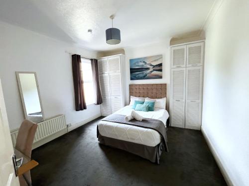 Newly Refurbished 2 Bedroom Flat - Long stays AVL في Norbury: غرفة نوم صغيرة مع سرير ومرآة
