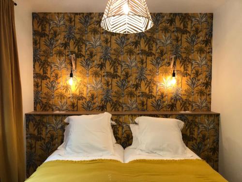 a bed with two pillows in a room with a wallpaper at Charmant Gîte Familial Rénové avec 3 Chambres, Cheminée et Jardin, Proche Le Mans - FR-1-410-332 in Le Mans