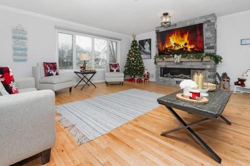 a living room with a fireplace and a christmas tree at Charming riverside cottage, walk to beach in Wasaga Beach