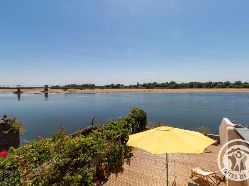 a yellow umbrella sitting on a dock next to a river at Maison Authentique sur 3 Niveaux avec Terrasse et Vue Loire - FR-1-622-38 in Ingrandes
