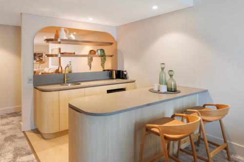 a kitchen with a counter and two chairs and a sink at Amora Hotel Brisbane in Brisbane