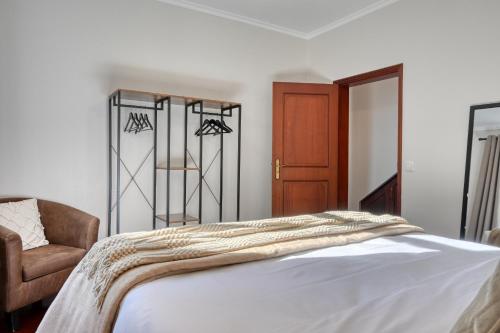 a bedroom with a bed and a chair at Freitas Paradise, a Home in Madeira in Ponta do Sol