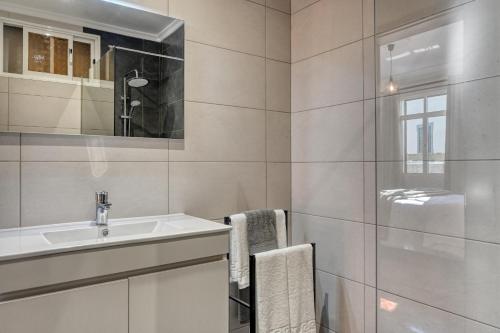 La salle de bains blanche est pourvue d'un lavabo et d'un miroir. dans l'établissement Freitas Paradise, a Home in Madeira, à Ponta do Sol