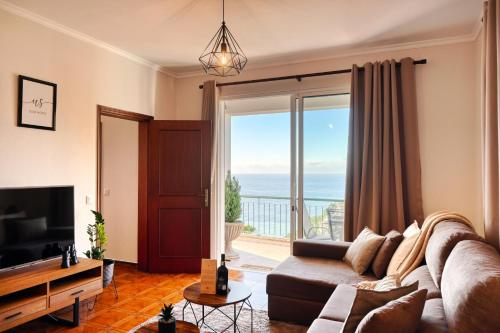 a living room with a couch and a large window at Freitas Paradise, a Home in Madeira in Ponta do Sol