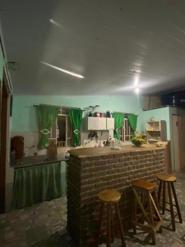 a kitchen with a brick counter and stools at Pousada Matriz in São Thomé das Letras