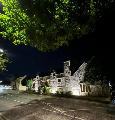 an old building with lights on a street at night at The Old Manor House Hotel in Keynsham