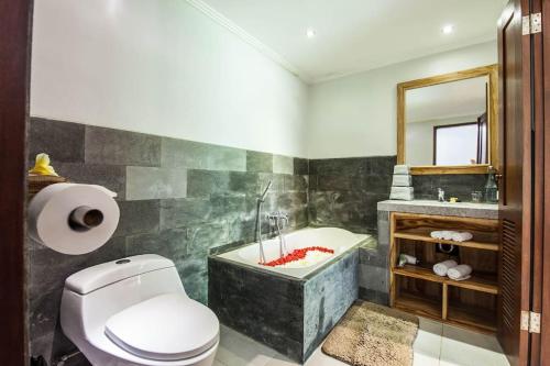 a bathroom with a tub and a toilet and a sink at Villa Alam Surya Ubud in Ubud