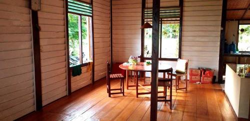 una sala da pranzo con tavolo, sedie e finestre di Bogani-Cottages a Beniha