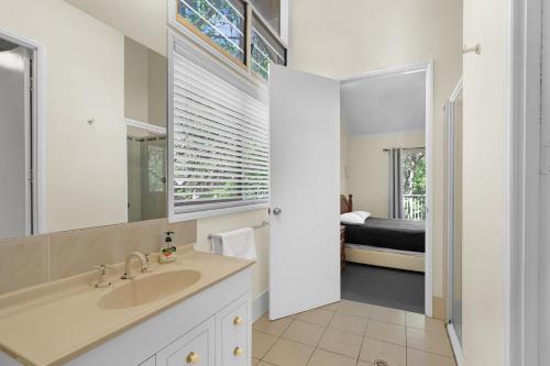 een badkamer met een wastafel en een spiegel en een slaapkamer bij Amaroo House in Point Lookout