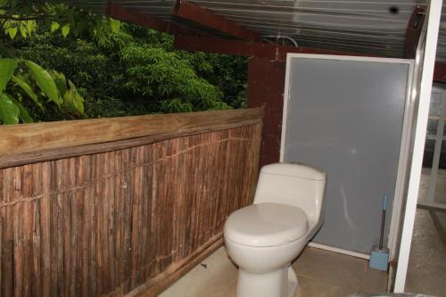 Glamping Bio Coliving Tayrona في سانتا مارتا: حمام مع مرحاض بجانب سياج خشبي