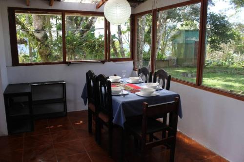 a dining room with a table and chairs and windows at Casa Luka in Turrialba