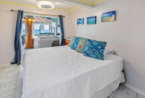 a bedroom with a white bed with a blue pillow at Corner Luxury Ethereal Hawaii Beachfront Estate for Monthly Rental with Private Beach & 3 Beachfront Jacuzzis & Snorkeling Reef & Jurassic Park Film Site in Punaluu
