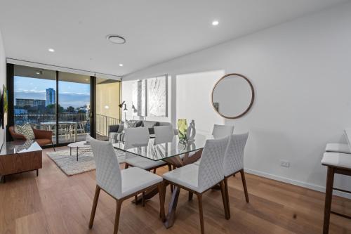 a dining room with a glass table and chairs at The Riverview - Brand New Modern 2BR with King Bed, Parking & Pool in Gold Coast