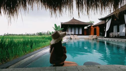 a statue of a person sitting next to a swimming pool at Kayangan Villa Ubud in Tegalalang