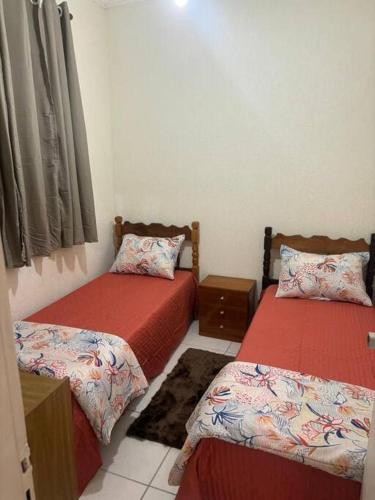 Cette chambre comprend 2 lits avec des draps rouges. dans l'établissement Apartamento 108 Centro Caragua, à Caraguatatuba
