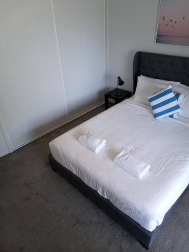 Una cama blanca con almohadas azules y blancas. en Maroochy Sands Holiday Apartments, en Maroochydore