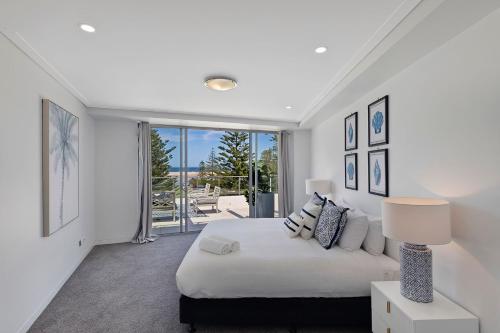 a white bedroom with a bed and a large window at Coast Luxury Apartments 17 in The Entrance