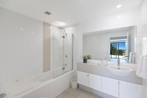 a white bathroom with a sink and a shower at Coast Luxury Apartments 17 in The Entrance