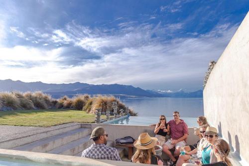 a group of people sitting on a wall near the water at Lakestone Lodge in Lake Pukaki