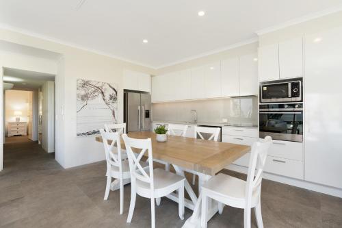 a kitchen with a wooden table and white cabinets at Noosa International Resort in Noosa Heads