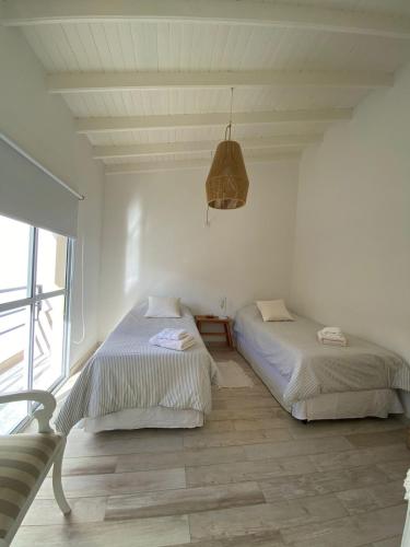 two beds in a white room with a window at Benarés in Puerto Madryn