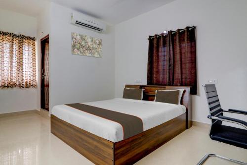 een slaapkamer met een bed en een stoel bij Capital O S V Residency Nalagandla in Hyderabad