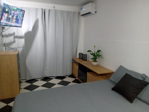 Un dormitorio con una cama y una mesa con una planta en Departamento monoambiente Belgrano R en Buenos Aires
