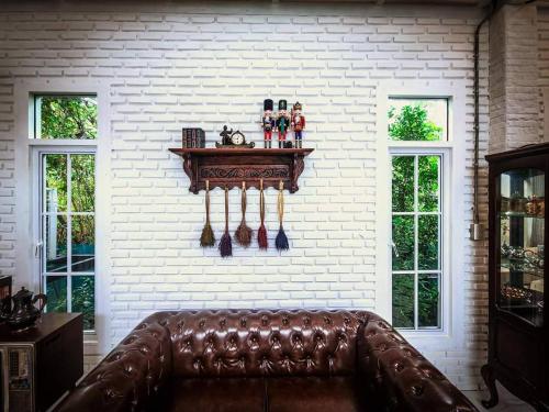 a leather couch in a room with a white brick wall at เรินนายหัว by KOYAD RESORT in Ban Wat Khao